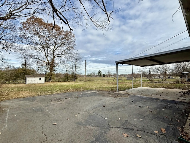 exterior space featuring driveway, a storage unit, a carport, and an outbuilding