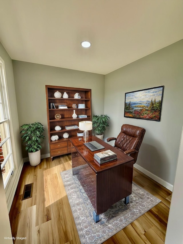 office space with baseboards, visible vents, and light wood-style floors