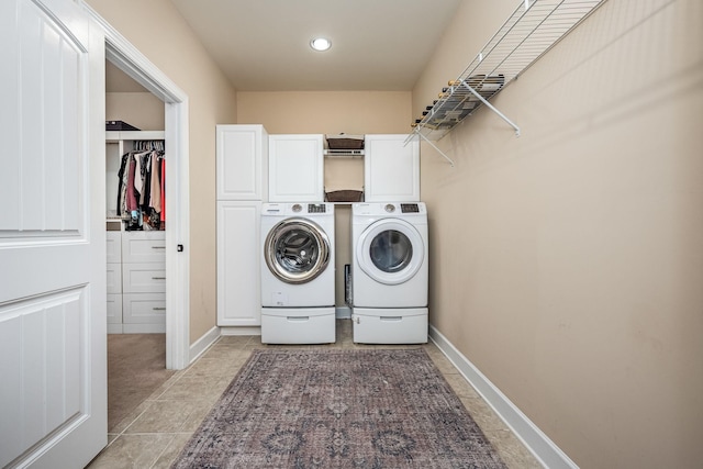 laundry room featuring cabinets, light tile patterned floors, and washing machine and clothes dryer