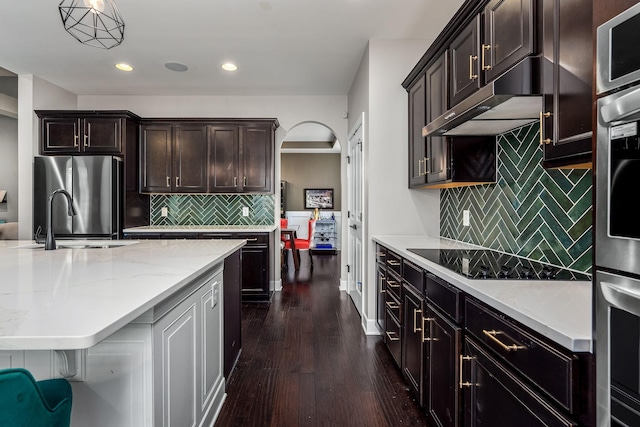 kitchen with dark hardwood / wood-style floors, stainless steel fridge, hanging light fixtures, and tasteful backsplash