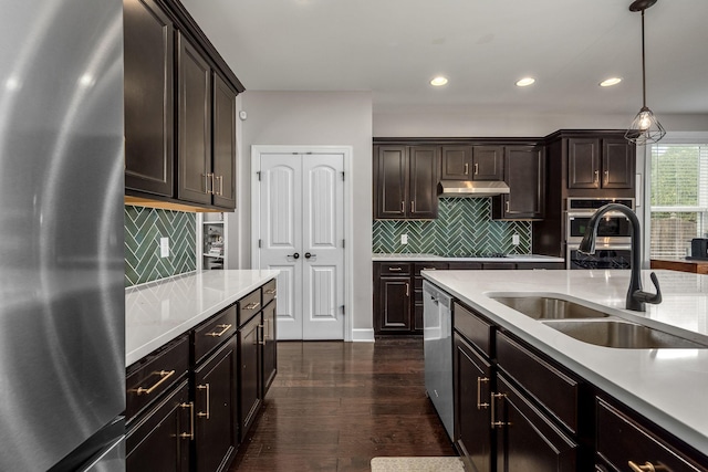 kitchen featuring dark brown cabinetry, sink, stainless steel appliances, dark hardwood / wood-style floors, and decorative light fixtures