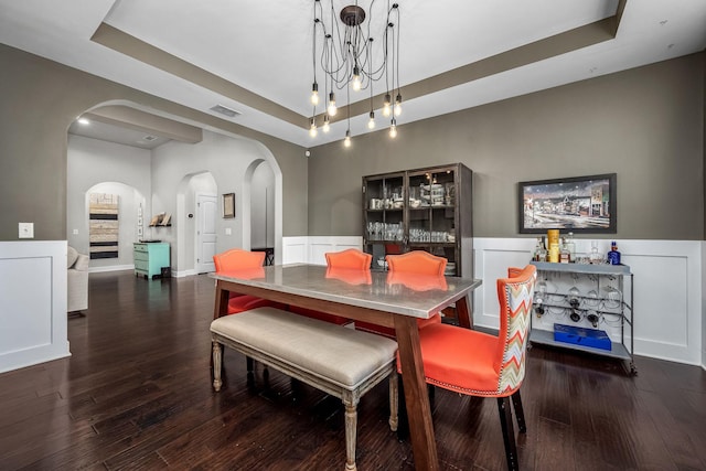 dining room with a raised ceiling, dark hardwood / wood-style floors, and a notable chandelier