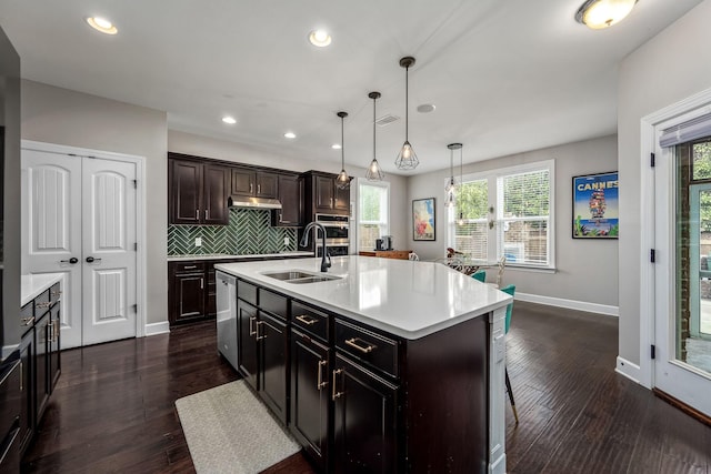 kitchen featuring decorative light fixtures, a center island with sink, dark wood-type flooring, and sink