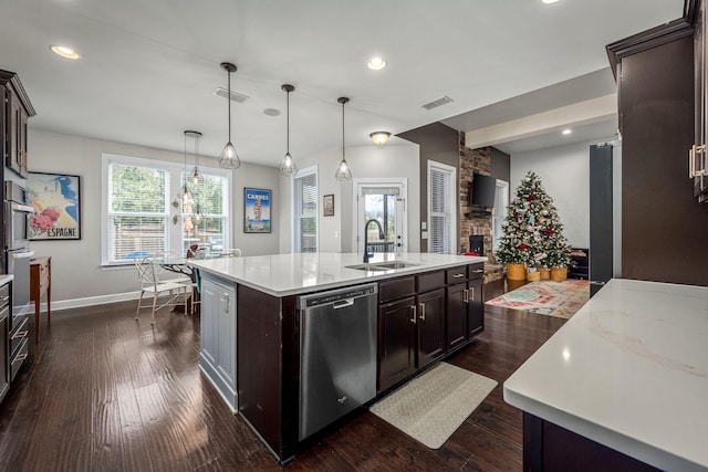 kitchen featuring dishwasher, sink, dark wood-type flooring, pendant lighting, and a center island with sink