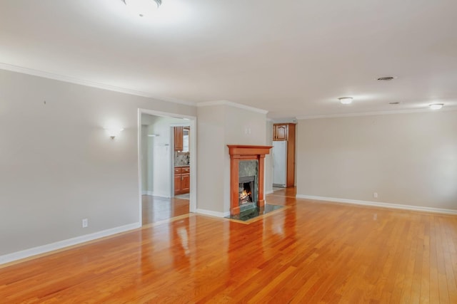 unfurnished living room with light hardwood / wood-style floors, ornamental molding, and a premium fireplace