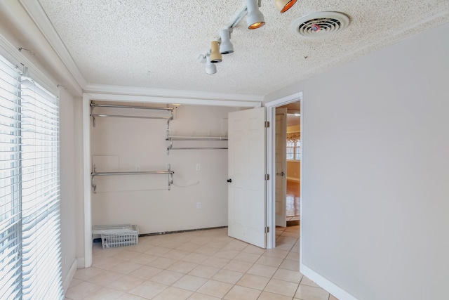 unfurnished bedroom featuring light tile patterned floors, a textured ceiling, and a closet