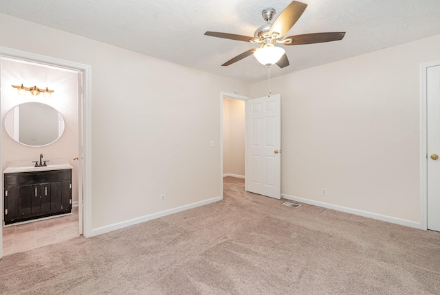 unfurnished bedroom featuring ensuite bathroom, ceiling fan, light colored carpet, and sink