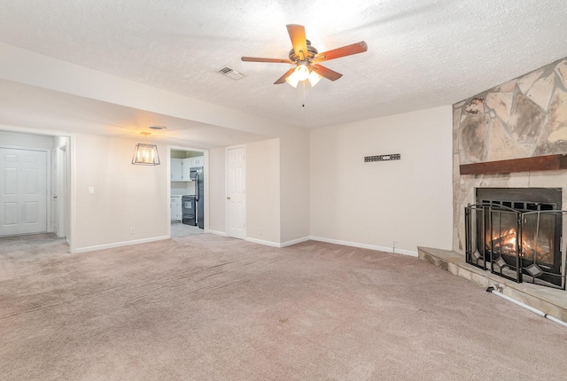 unfurnished living room featuring a stone fireplace, ceiling fan, light colored carpet, and a textured ceiling