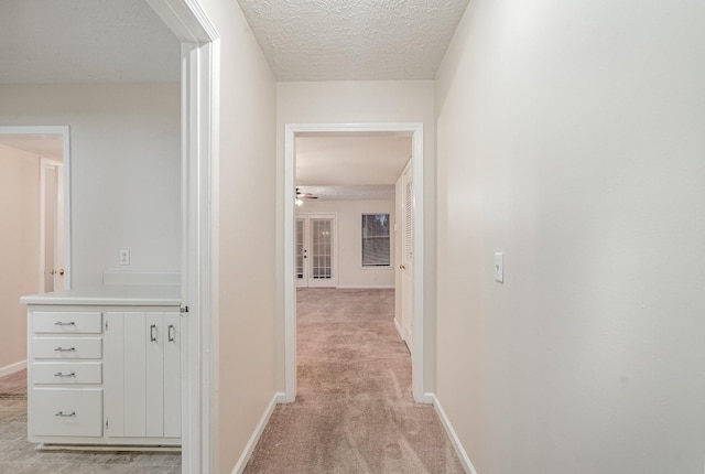 corridor featuring a textured ceiling and light colored carpet