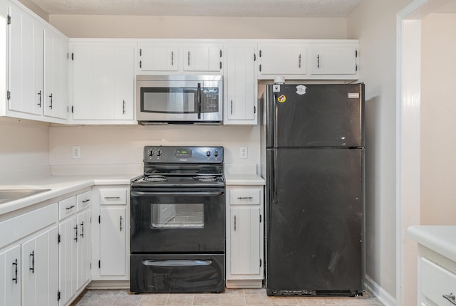 kitchen with light tile patterned flooring, white cabinetry, and black appliances