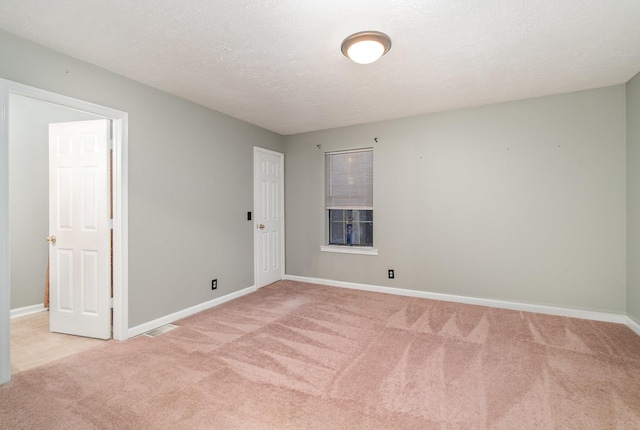 unfurnished room with a textured ceiling and light carpet