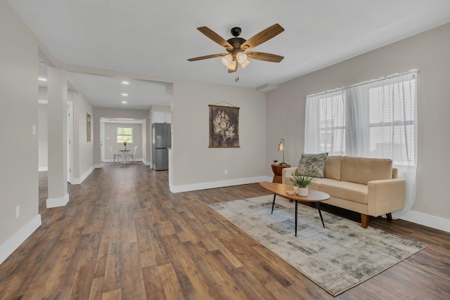 living room featuring ceiling fan and dark wood-type flooring