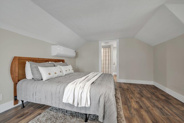 bedroom featuring dark hardwood / wood-style flooring, an AC wall unit, a textured ceiling, and vaulted ceiling