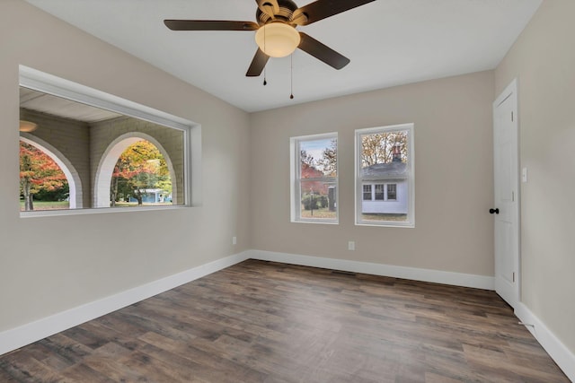 empty room featuring ceiling fan, plenty of natural light, and dark hardwood / wood-style floors