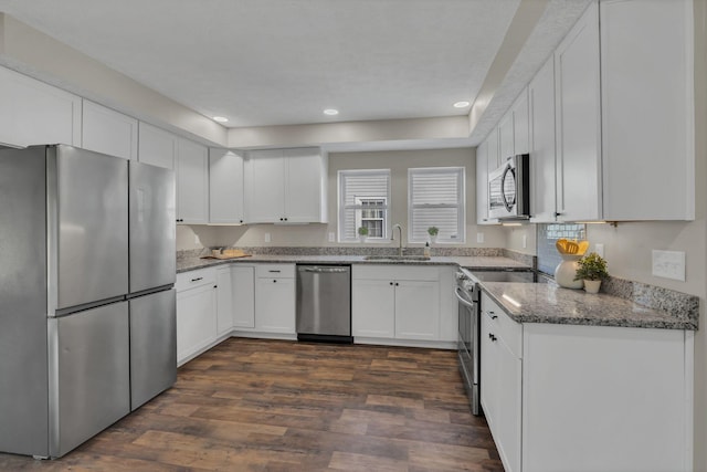 kitchen featuring appliances with stainless steel finishes, dark wood-type flooring, sink, stone countertops, and white cabinetry