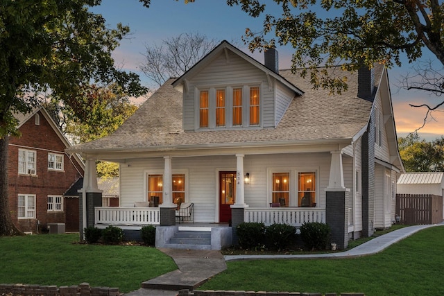 view of front facade featuring a lawn, a porch, and central air condition unit