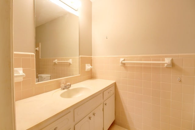 bathroom featuring vanity, toilet, and tile walls