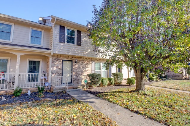 townhome / multi-family property featuring covered porch and a front yard