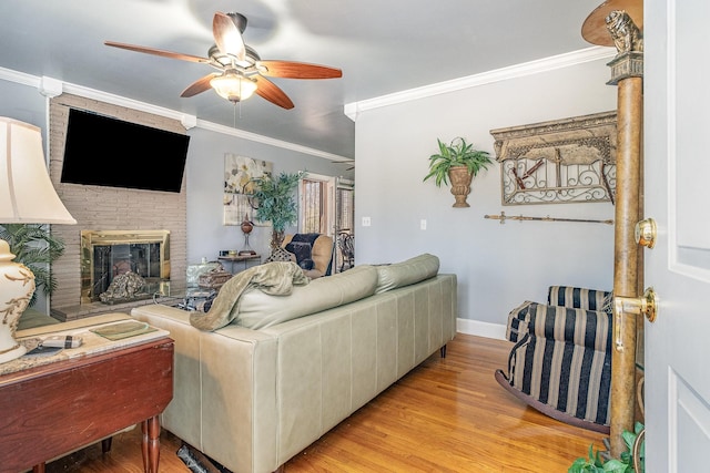 living room with crown molding, ceiling fan, light hardwood / wood-style floors, and a brick fireplace