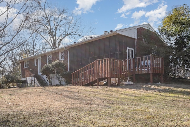 rear view of house featuring a yard, a deck, and a sunroom