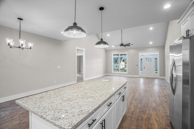 kitchen featuring open floor plan, a kitchen island, freestanding refrigerator, and white cabinets