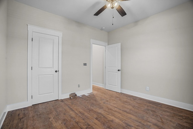 unfurnished bedroom featuring ceiling fan, dark wood-type flooring, and baseboards