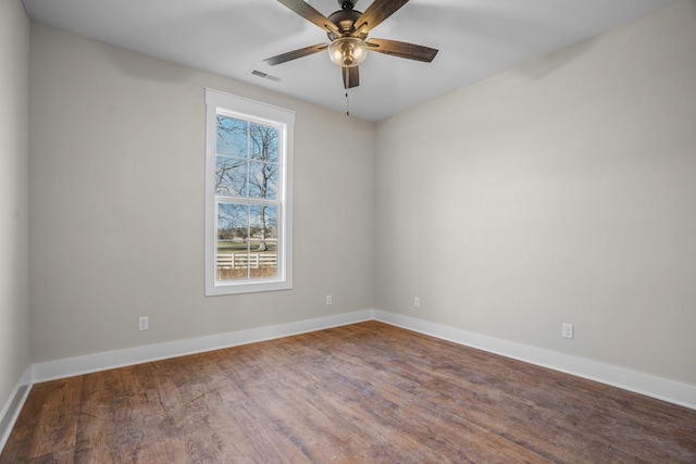 empty room featuring a ceiling fan, baseboards, visible vents, and wood finished floors