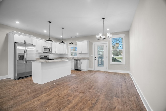 kitchen with hanging light fixtures, a kitchen island, appliances with stainless steel finishes, and white cabinets