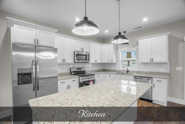 kitchen featuring stainless steel appliances, pendant lighting, white cabinets, and a sink