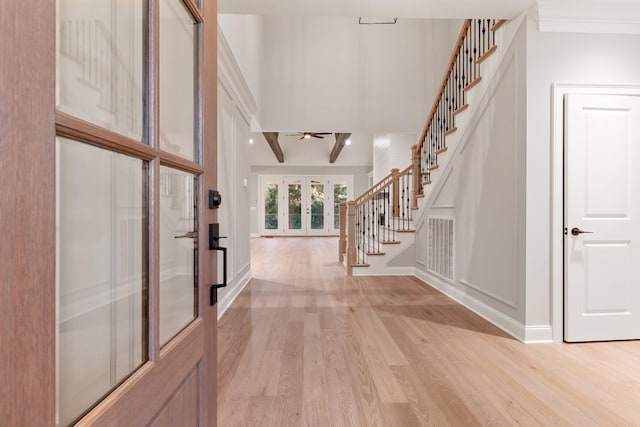 foyer entrance with crown molding, french doors, and light wood-type flooring