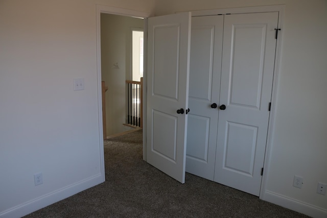 unfurnished bedroom with dark carpet and a closet