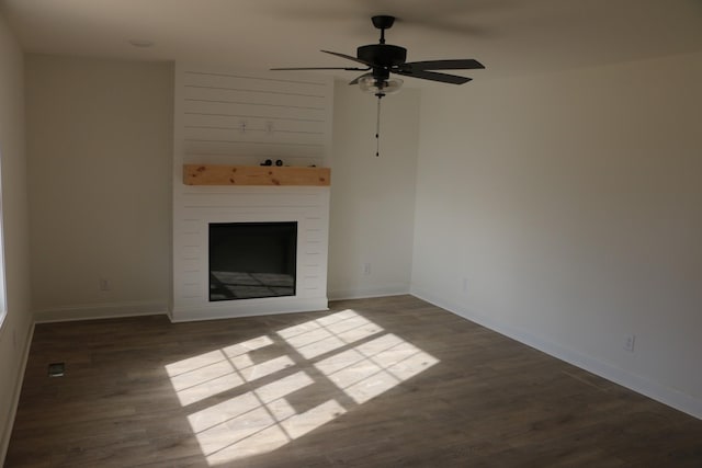 unfurnished living room with ceiling fan, a large fireplace, and dark hardwood / wood-style flooring