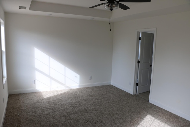 carpeted empty room featuring ceiling fan and a raised ceiling