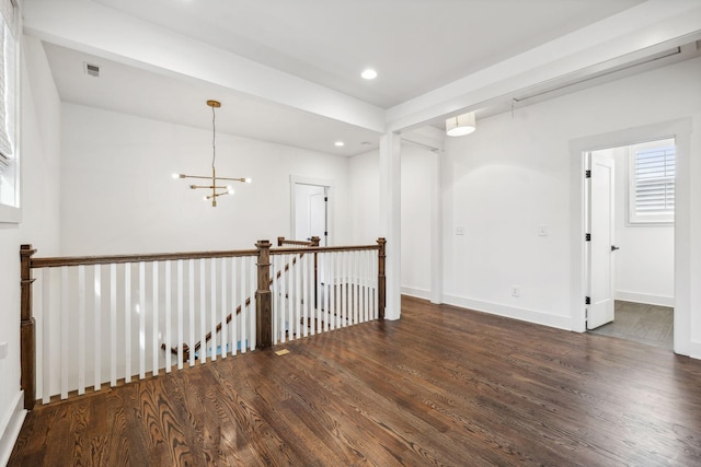 spare room with a chandelier and dark hardwood / wood-style floors