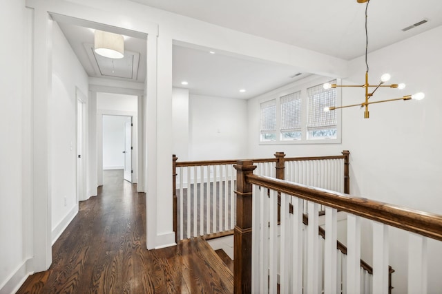 hallway with dark hardwood / wood-style floors and an inviting chandelier