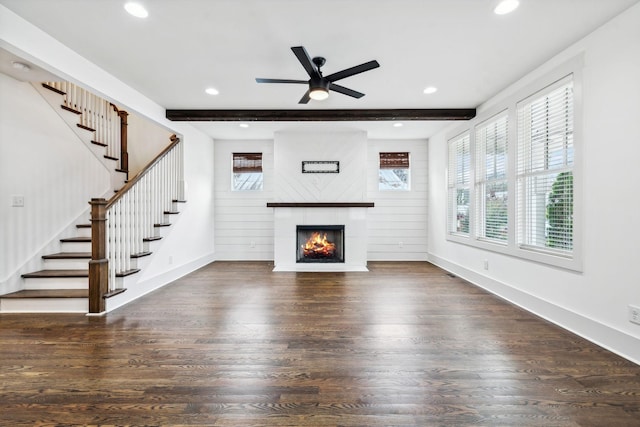 unfurnished living room featuring beam ceiling, ceiling fan, dark wood-type flooring, wood walls, and a fireplace