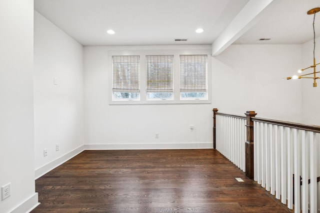 unfurnished room with beam ceiling, dark wood-type flooring, and an inviting chandelier