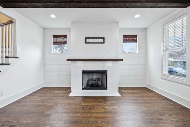 unfurnished living room featuring a fireplace, dark hardwood / wood-style floors, and wood walls