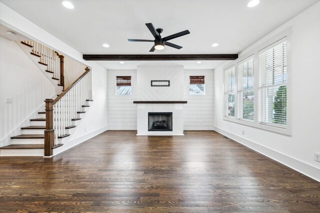 unfurnished living room featuring a large fireplace, ceiling fan, dark hardwood / wood-style flooring, and beam ceiling