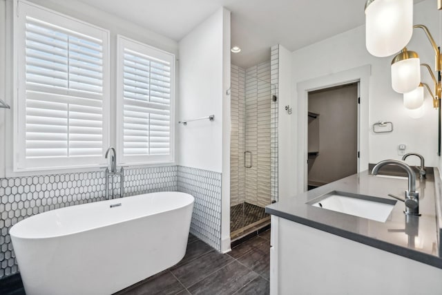 bathroom with shower with separate bathtub, vanity, and tile walls