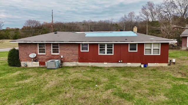 back of property featuring central AC unit and a lawn