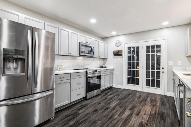 kitchen with decorative backsplash, stainless steel appliances, gray cabinets, and dark wood-type flooring