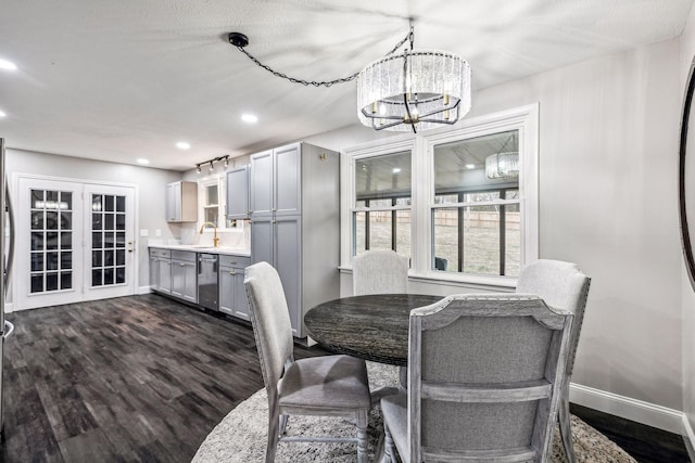 dining room featuring sink, french doors, dark wood-type flooring, a notable chandelier, and a textured ceiling