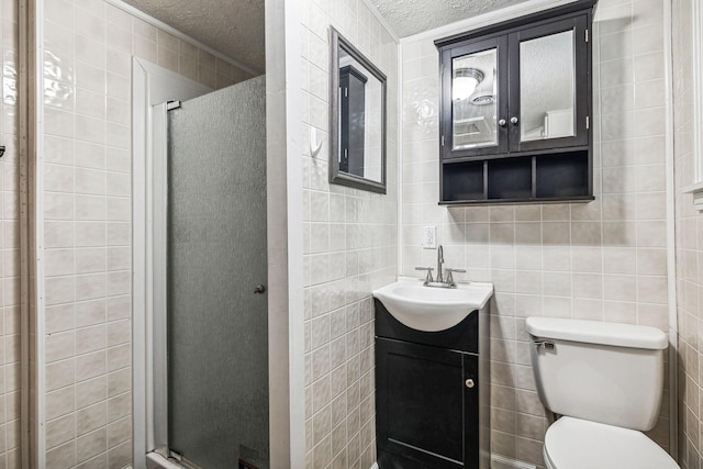 bathroom with vanity, a textured ceiling, an enclosed shower, and tile walls