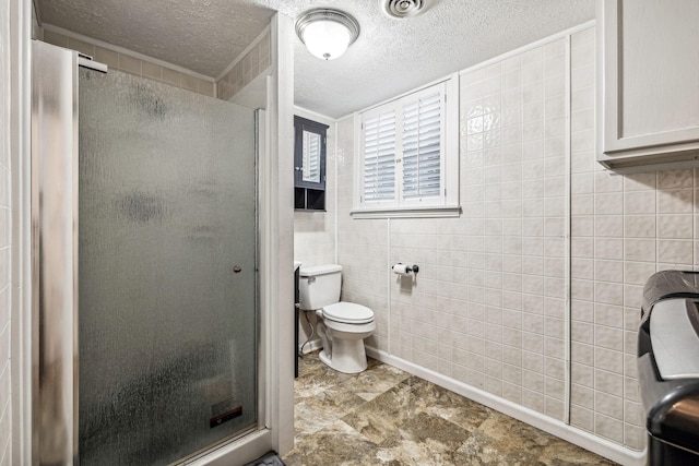 bathroom featuring tile walls, a shower with shower door, a textured ceiling, and toilet