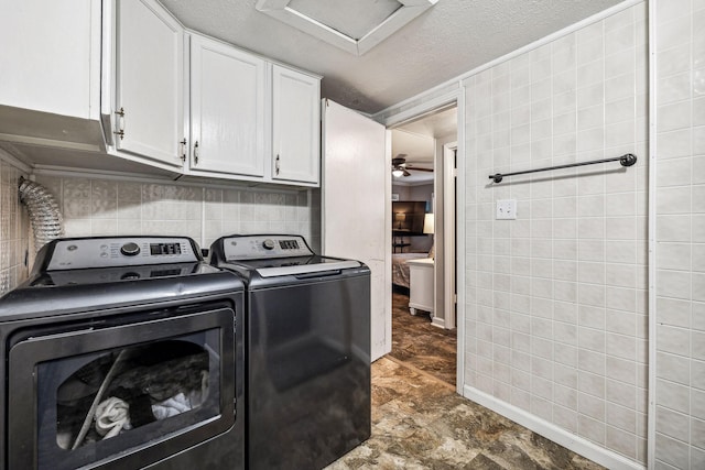 clothes washing area with ceiling fan, cabinets, separate washer and dryer, and a textured ceiling