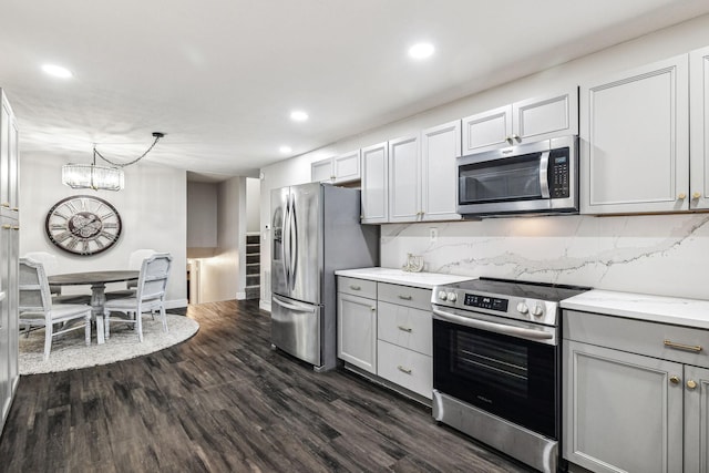 kitchen with gray cabinetry, dark wood-type flooring, hanging light fixtures, appliances with stainless steel finishes, and a chandelier