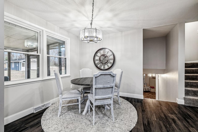 dining room featuring a textured ceiling, a notable chandelier, and dark wood-type flooring