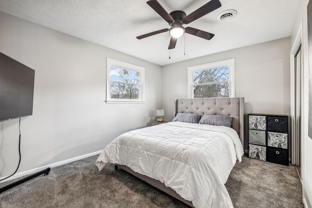 carpeted bedroom featuring ceiling fan, a textured ceiling, and multiple windows