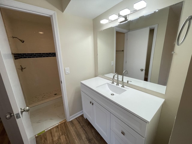 bathroom featuring vanity, a tile shower, and wood-type flooring